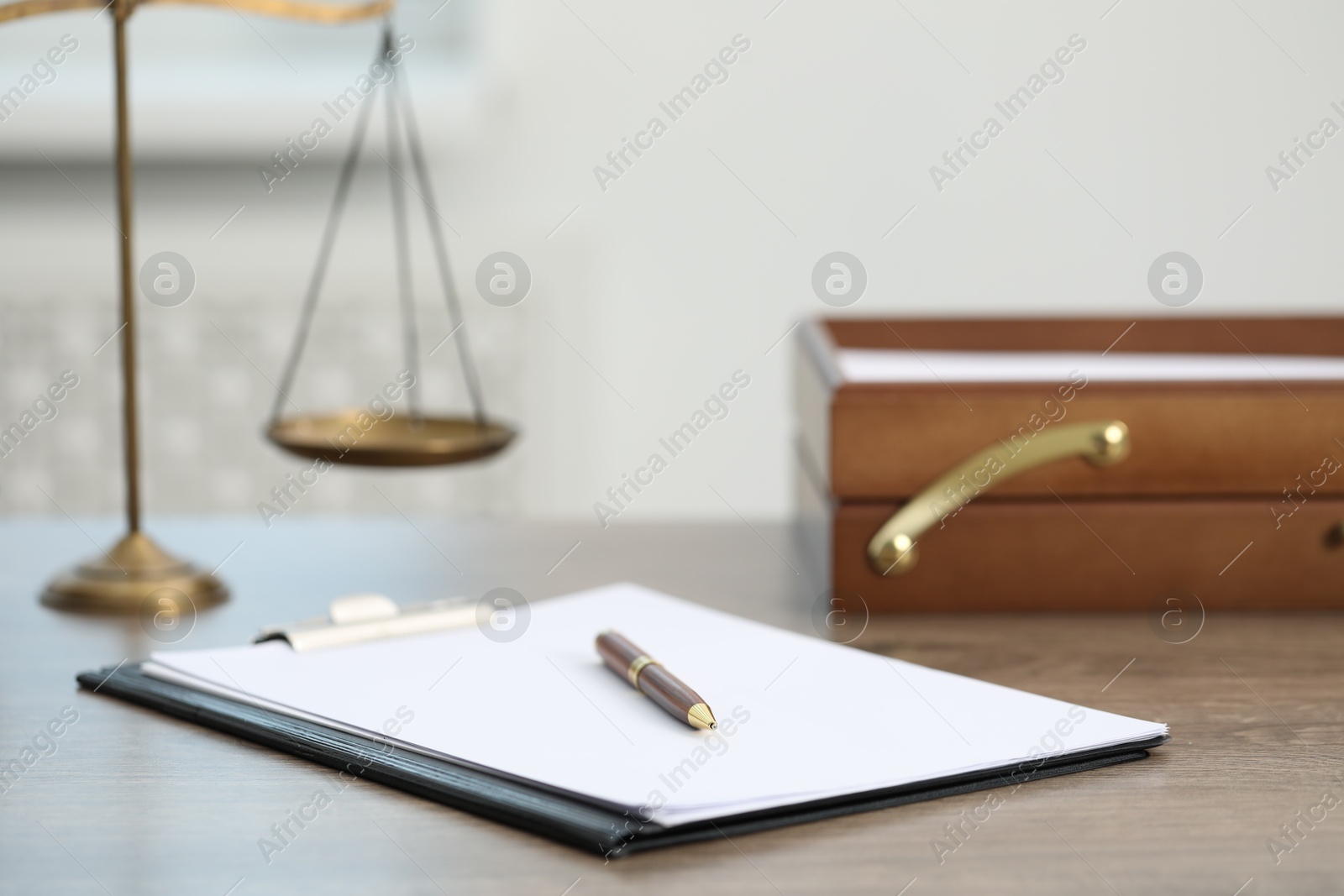 Photo of Judge's workplace with clipboard and scales on wooden table in office, closeup