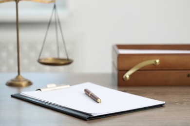 Photo of Judge's workplace with clipboard and scales on wooden table in office, closeup