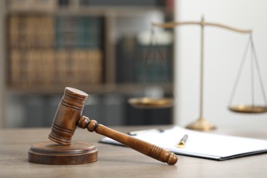 Photo of Judge's gavel, clipboard and scales on wooden table in office, closeup