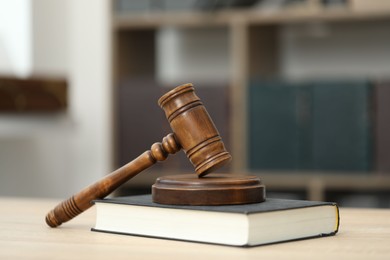 Photo of Judge's gavel and book on wooden table in office, closeup
