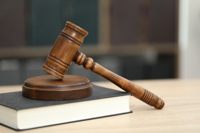 Photo of Judge's gavel and book on wooden table in office, closeup