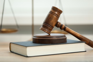 Photo of Judge's gavel and book on wooden table in office, closeup