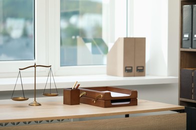 Photo of Judge's workplace with scales and stationery on wooden table in office