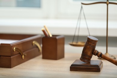 Photo of Judge's gavel and scales on wooden table in office, closeup