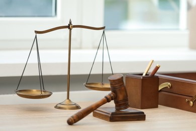 Photo of Judge's gavel and scales on wooden table in office