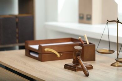 Photo of Judge's gavel and scales on wooden table in office
