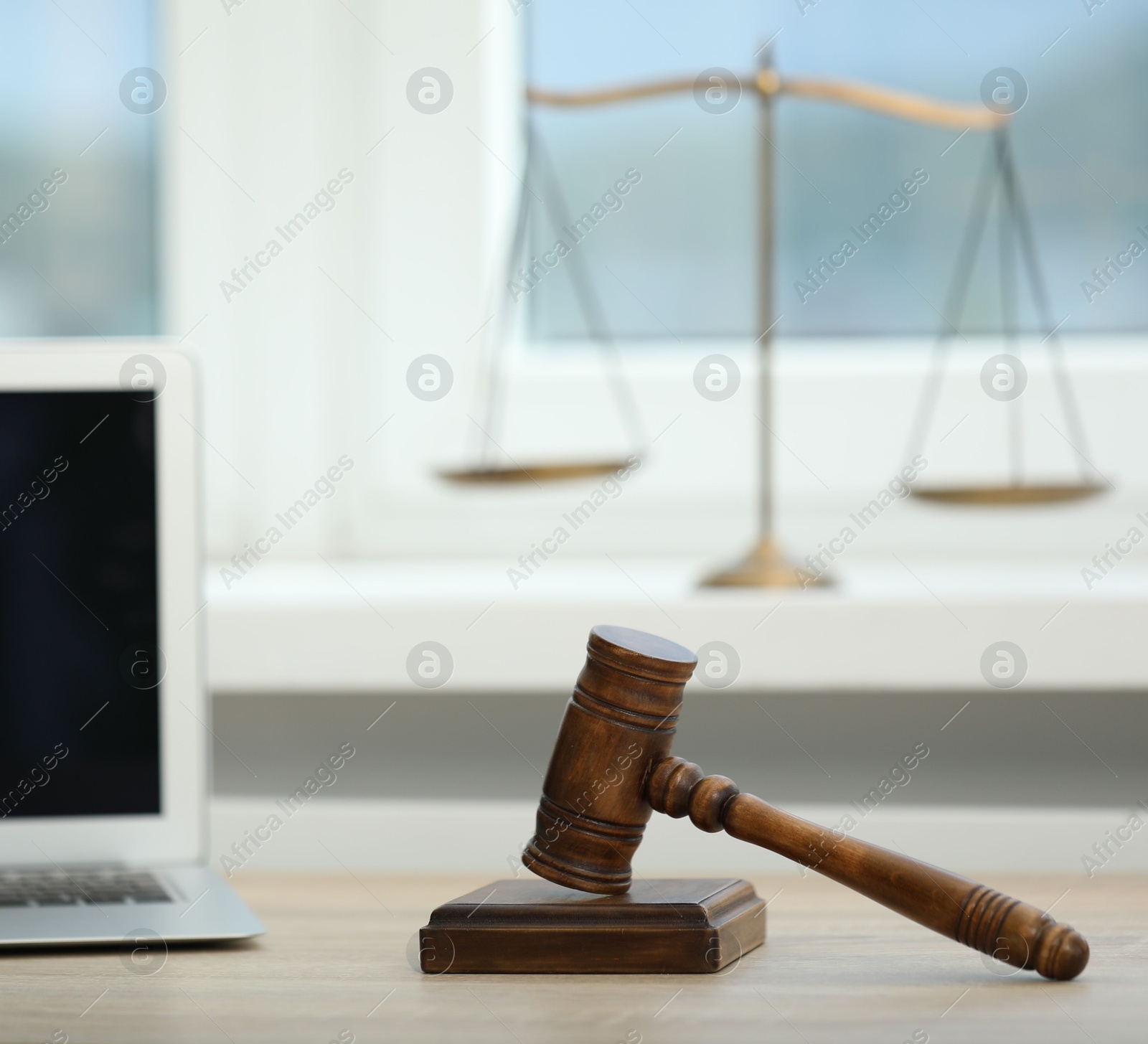 Laptop, judge's gavel and scales on wooden table in office Photo of Laptop, judge's gavel and scales on wooden table in office