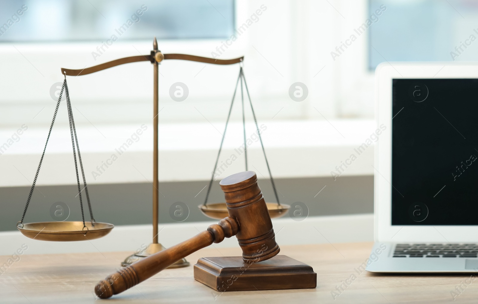Laptop, judge's gavel and scales on wooden table in office Photo of Laptop, judge's gavel and scales on wooden table in office