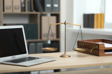Photo of Judge's workplace with laptop and scales on wooden table in office