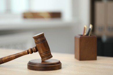 Photo of Judge's gavel and stationery on wooden table in office, closeup
