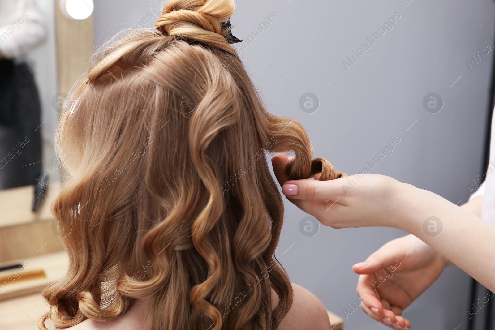 Hairdresser curling woman's hair in salon, closeup Photo of Hairdresser curling woman's hair in salon, closeup