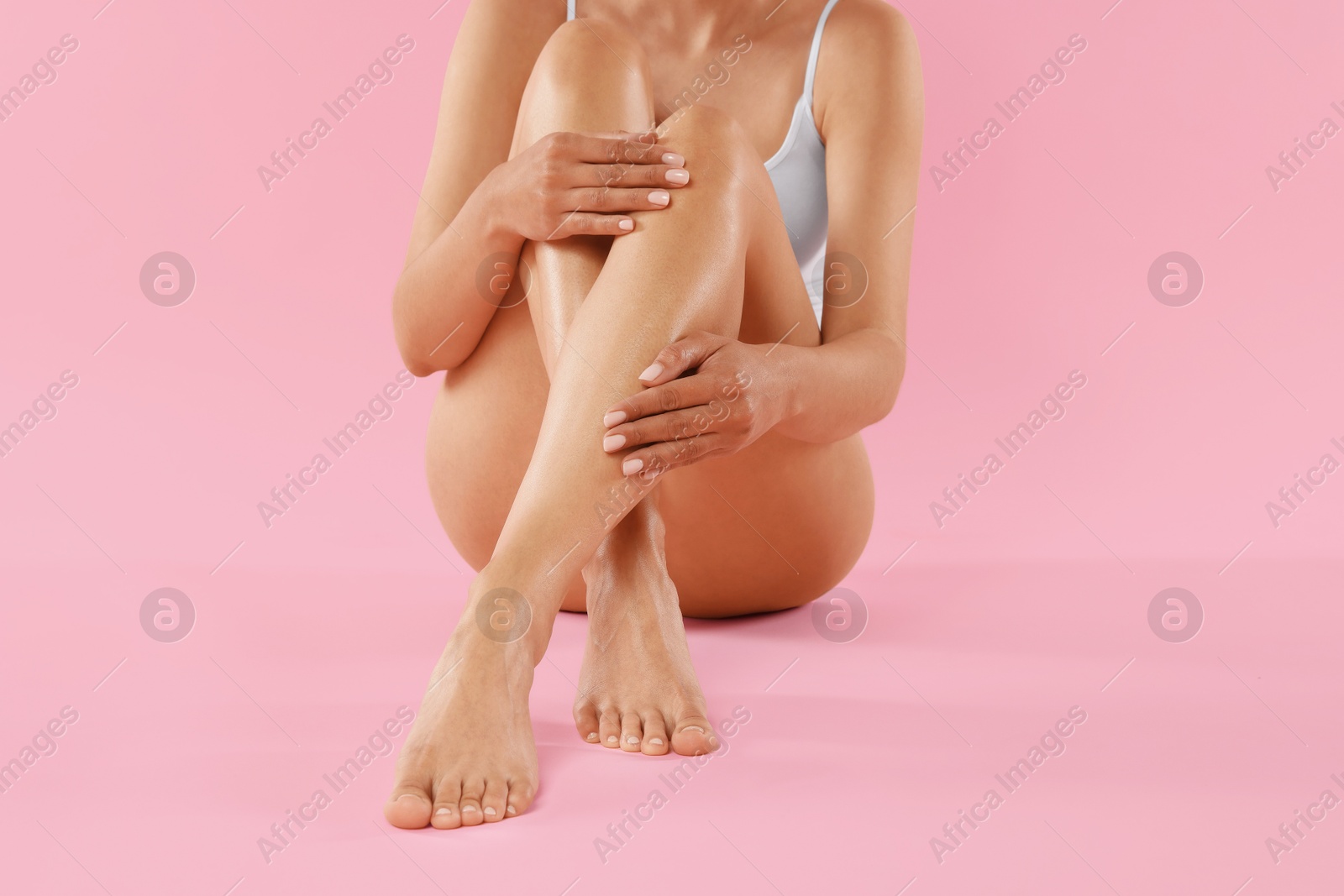 Woman with beautiful smooth legs after epilation on pink background, closeup Photo of Woman with beautiful smooth legs after epilation on pink background, closeup