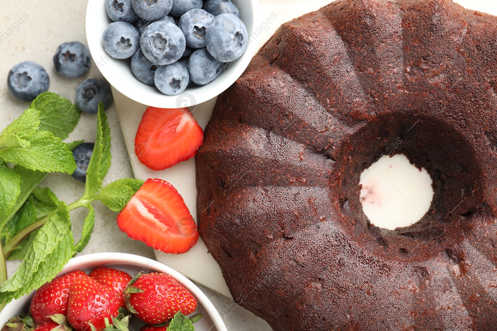 Tasty chocolate bundt cake and berries on light table, flat lay Photo of Tasty chocolate bundt cake and berries on light table, flat lay