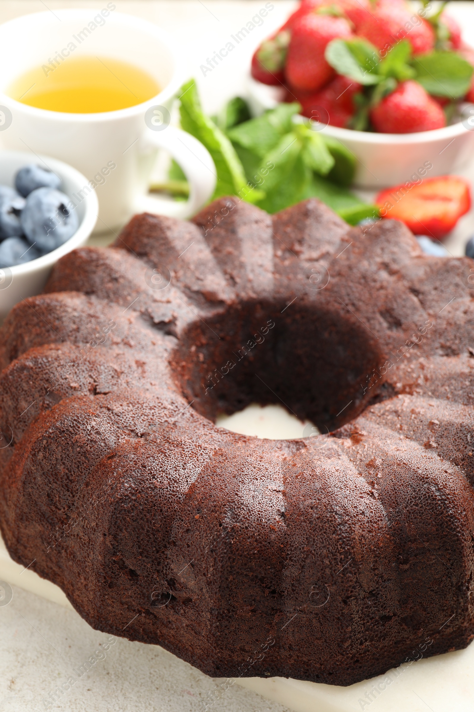 Tasty chocolate bundt cake, tea and berries on light table, closeup Photo of Tasty chocolate bundt cake, tea and berries on light table, closeup
