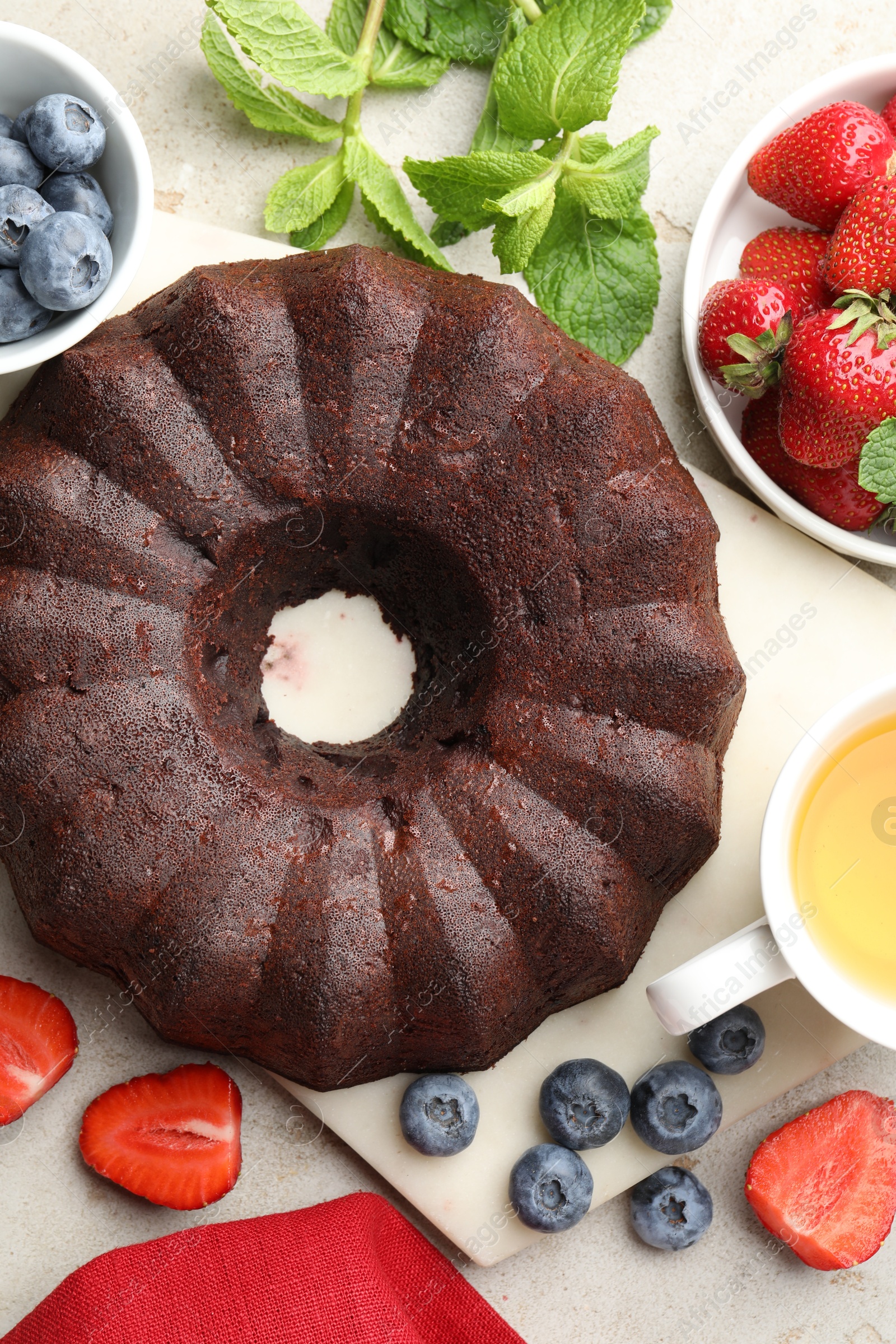 Tasty chocolate bundt cake, tea and berries on light table, flat lay Photo of Tasty chocolate bundt cake, tea and berries on light table, flat lay