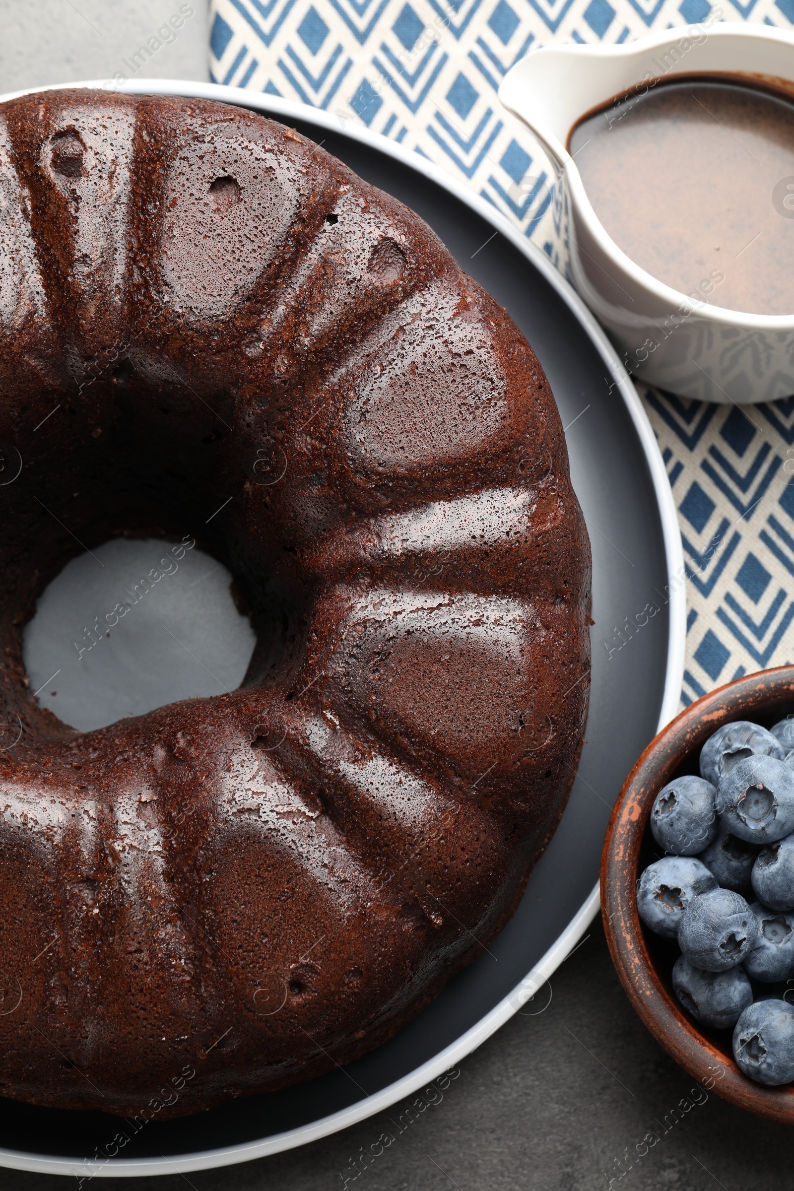 Tasty chocolate bundt cake and blueberries on grey table, top view Photo of Tasty chocolate bundt cake and blueberries on grey table, top view
