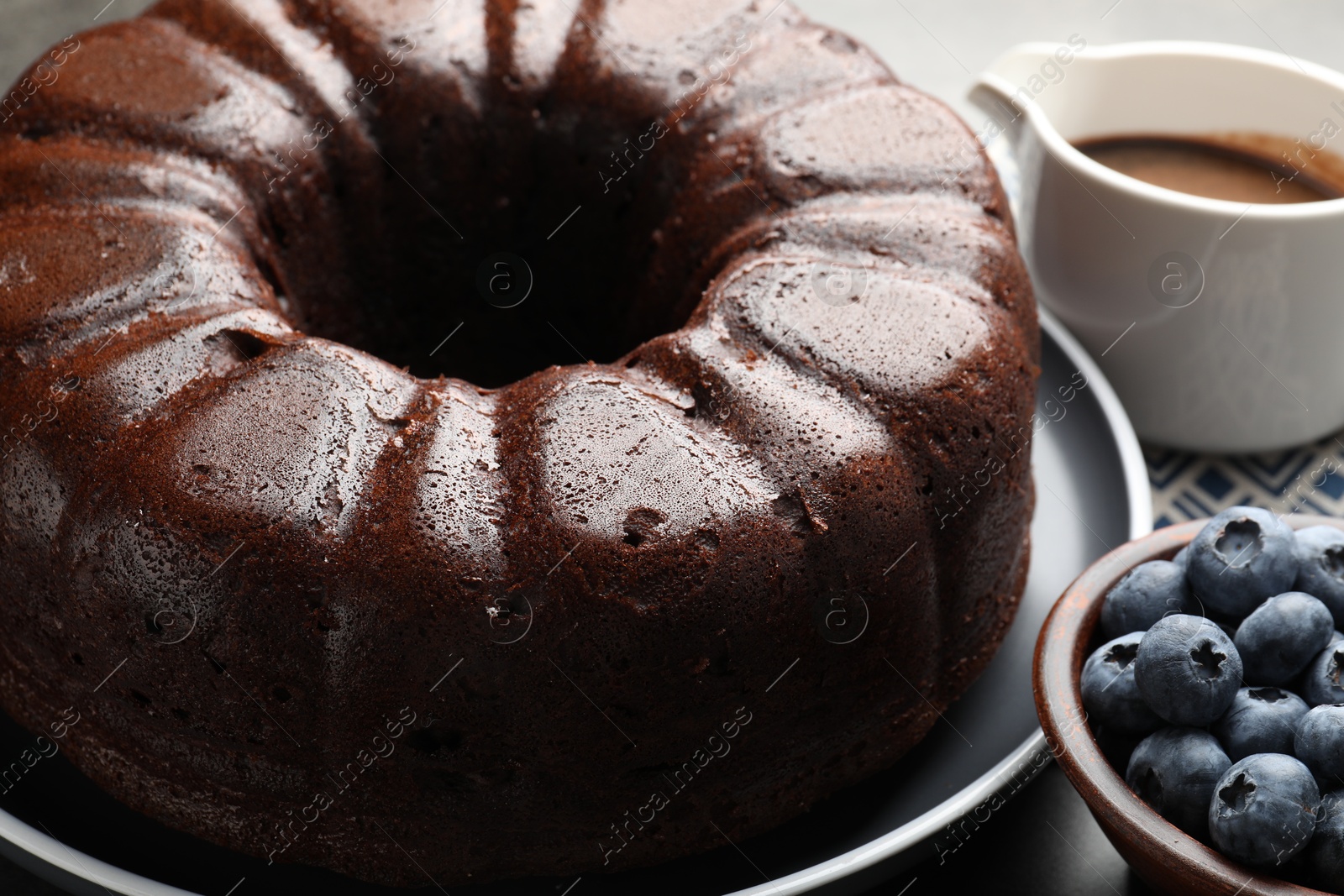 Tasty chocolate bundt cake and blueberries on grey table, closeup Photo of Tasty chocolate bundt cake and blueberries on grey table, closeup
