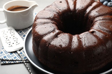 Photo of Tasty chocolate bundt cake and server on grey table, closeup