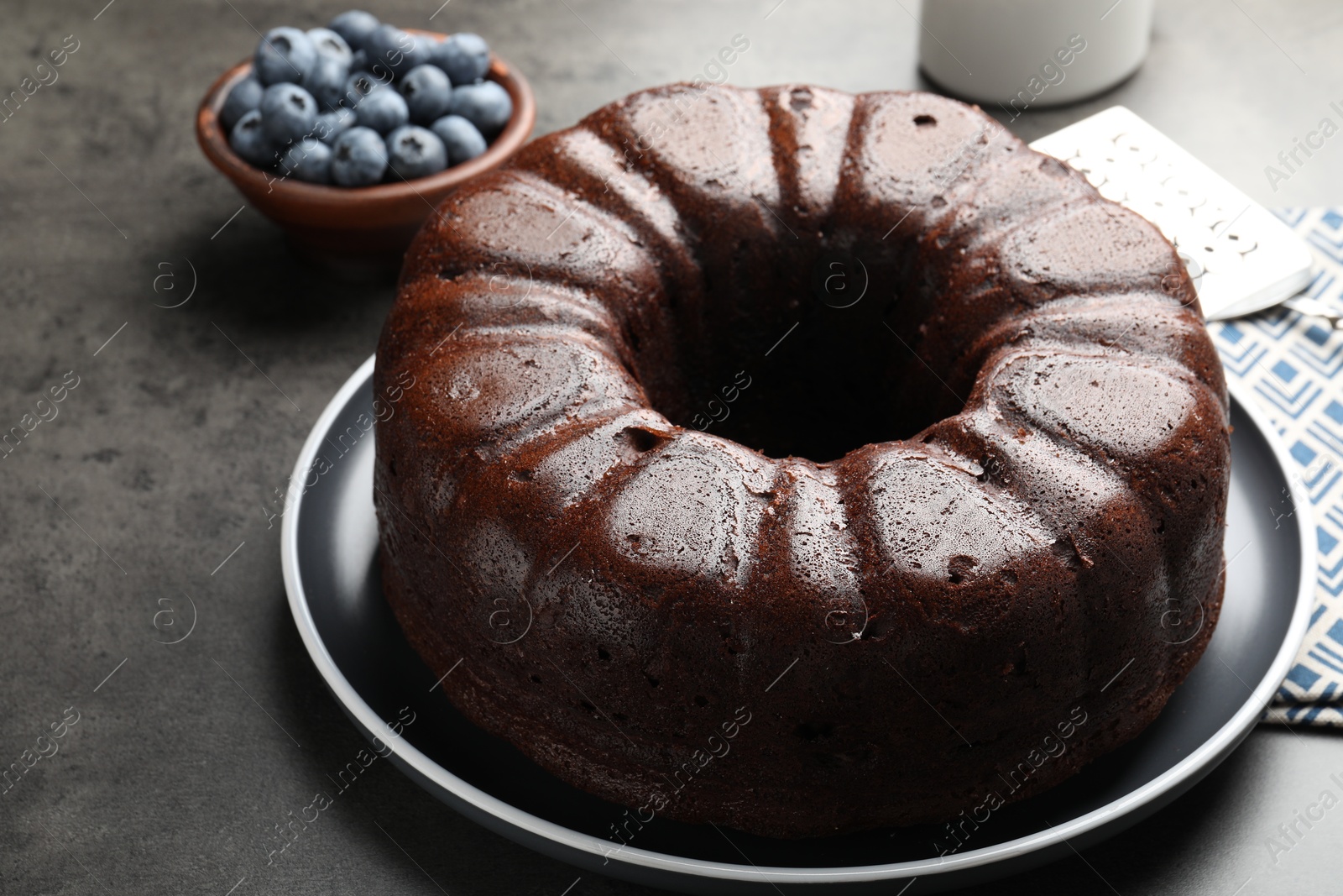 Tasty chocolate bundt cake and blueberries on grey table, closeup Photo of Tasty chocolate bundt cake and blueberries on grey table, closeup