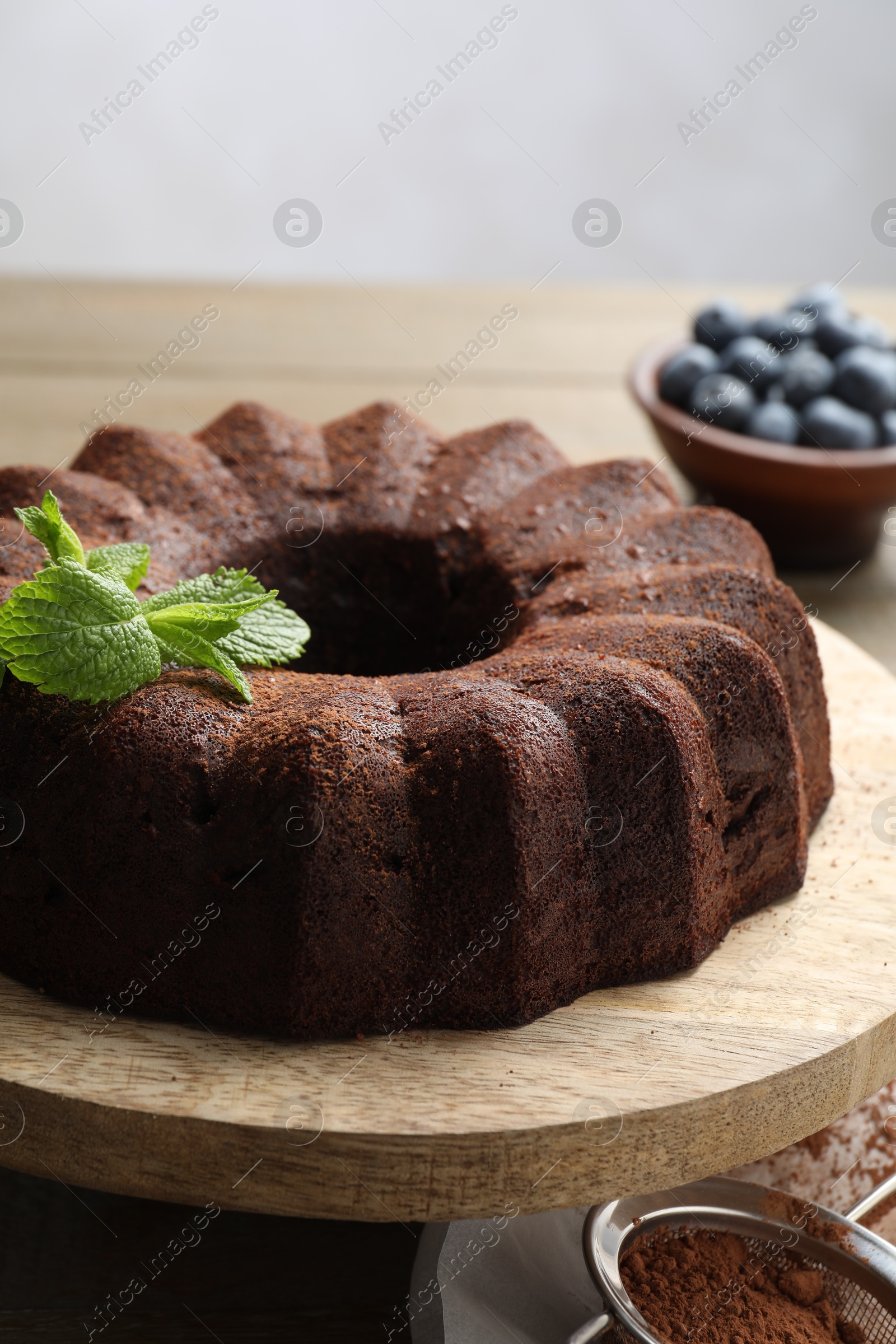 Tasty chocolate bundt cake with mint and blueberries on wooden table, closeup Photo of Tasty chocolate bundt cake with mint and blueberries on wooden table, closeup