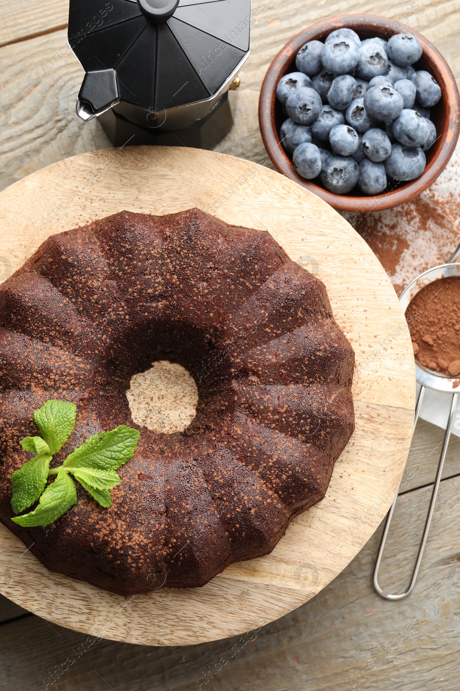 Tasty chocolate bundt cake with mint and blueberries on wooden table, flat lay Photo of Tasty chocolate bundt cake with mint and blueberries on wooden table, flat lay