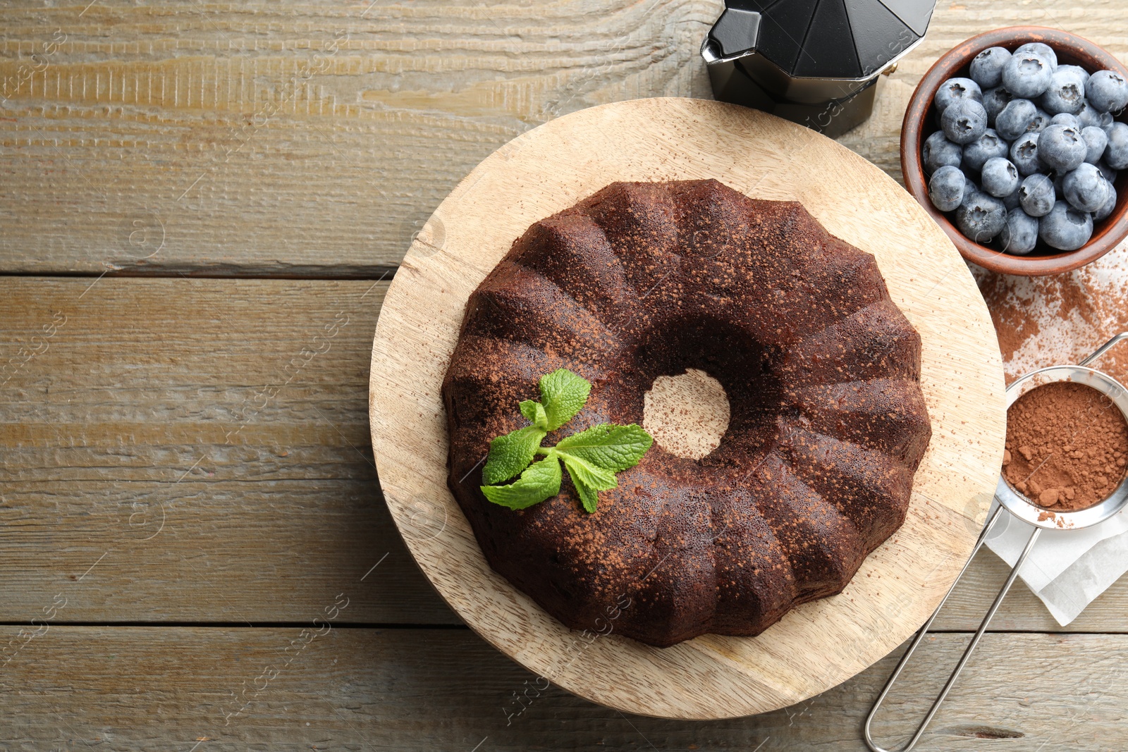 Tasty chocolate bundt cake with mint and blueberries on wooden table, flat lay. Space for text Photo of Tasty chocolate bundt cake with mint and blueberries on wooden table, flat lay. Space for text