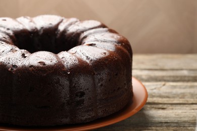 Photo of Tasty chocolate bundt cake on wooden table, closeup