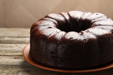 Photo of Tasty chocolate bundt cake on wooden table, closeup