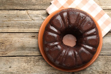 Photo of Tasty chocolate bundt cake on wooden table, top view. Space for text