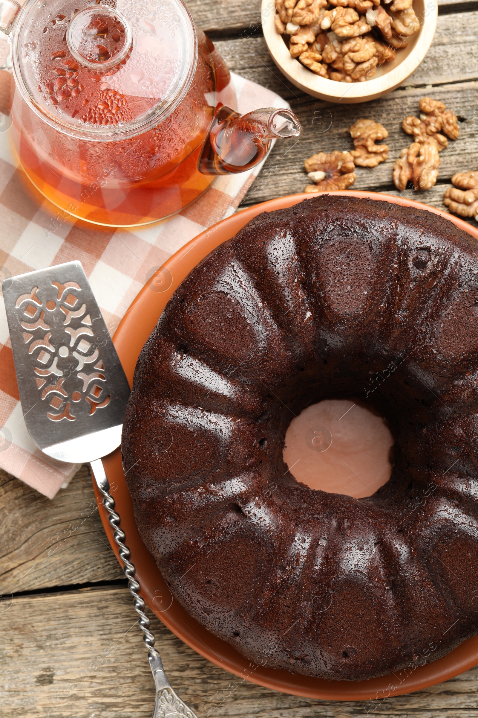 Tasty chocolate bundt cake, walnuts, tea and server on wooden table, flat lay Photo of Tasty chocolate bundt cake, walnuts, tea and server on wooden table, flat lay