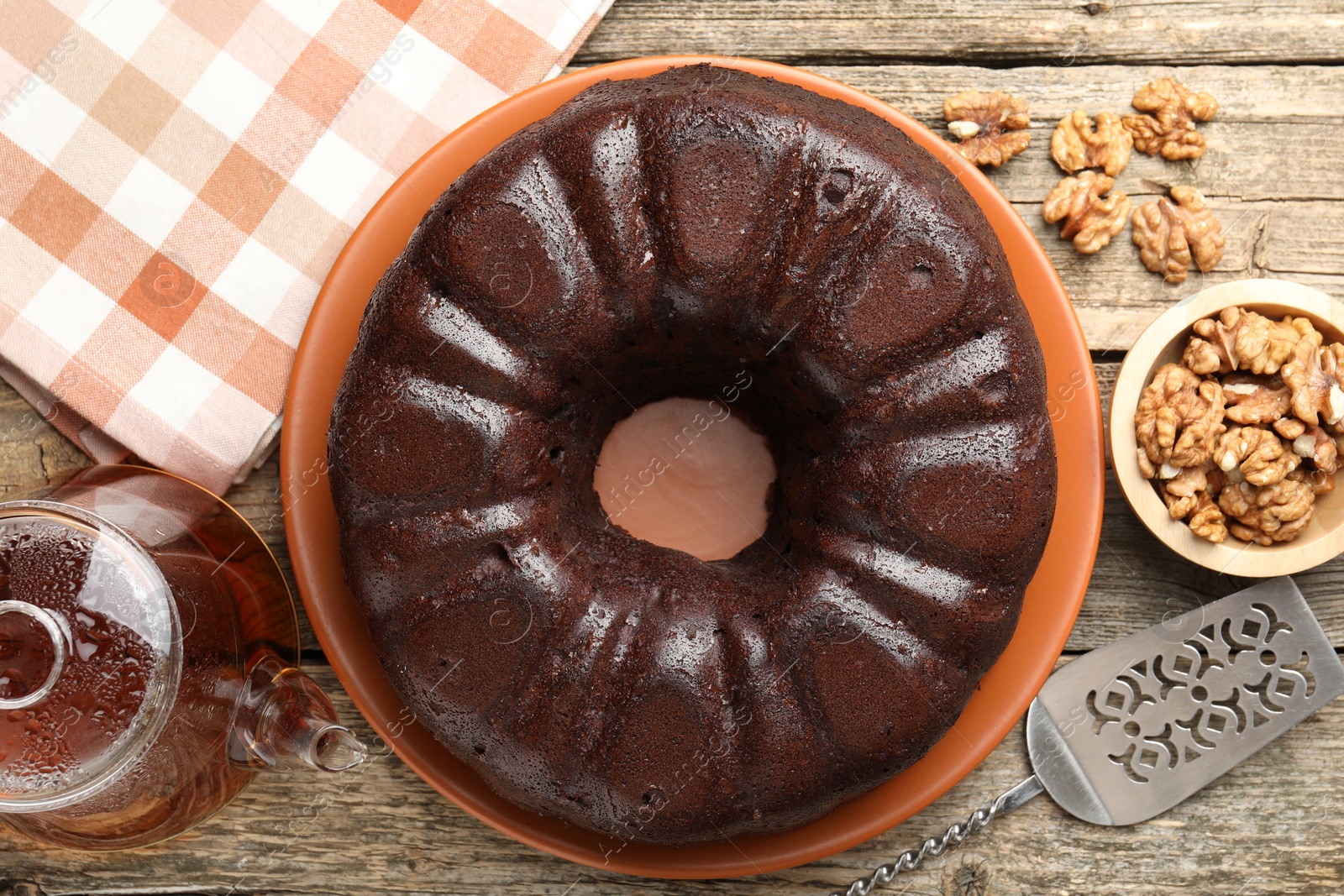 Tasty chocolate bundt cake, walnuts, tea and server on wooden table, flat lay Photo of Tasty chocolate bundt cake, walnuts, tea and server on wooden table, flat lay