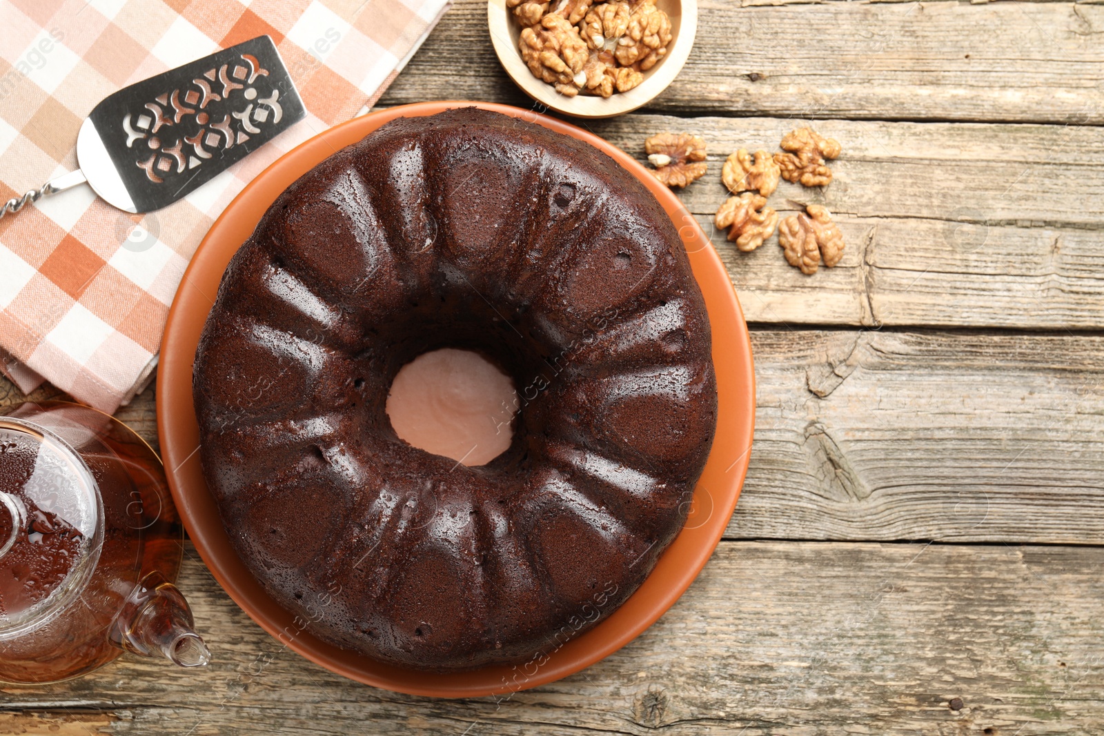 Tasty chocolate bundt cake, walnuts, tea and server on wooden table, flat lay Photo of Tasty chocolate bundt cake, walnuts, tea and server on wooden table, flat lay