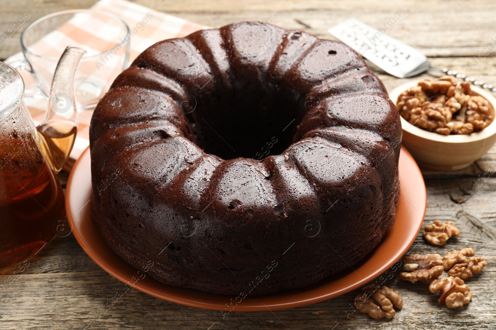 Tasty chocolate bundt cake, walnuts and tea on wooden table, closeup Photo of Tasty chocolate bundt cake, walnuts and tea on wooden table, closeup