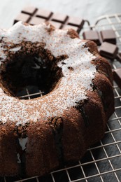 Photo of Tasty bundt cake with glaze and chocolate pieces on grey table, closeup
