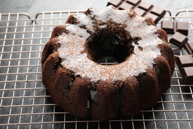 Photo of Tasty bundt cake with glaze and chocolate pieces on grey table, closeup