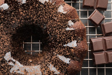 Photo of Tasty bundt cake with glaze and chocolate pieces on grey table, top view