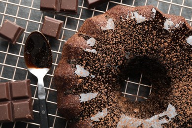 Photo of Tasty bundt cake with glaze and chocolate pieces on grey table, top view