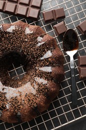 Photo of Tasty bundt cake with glaze and chocolate pieces on grey table, top view