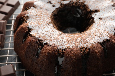 Photo of Tasty bundt cake with glaze and chocolate pieces on grey table, closeup