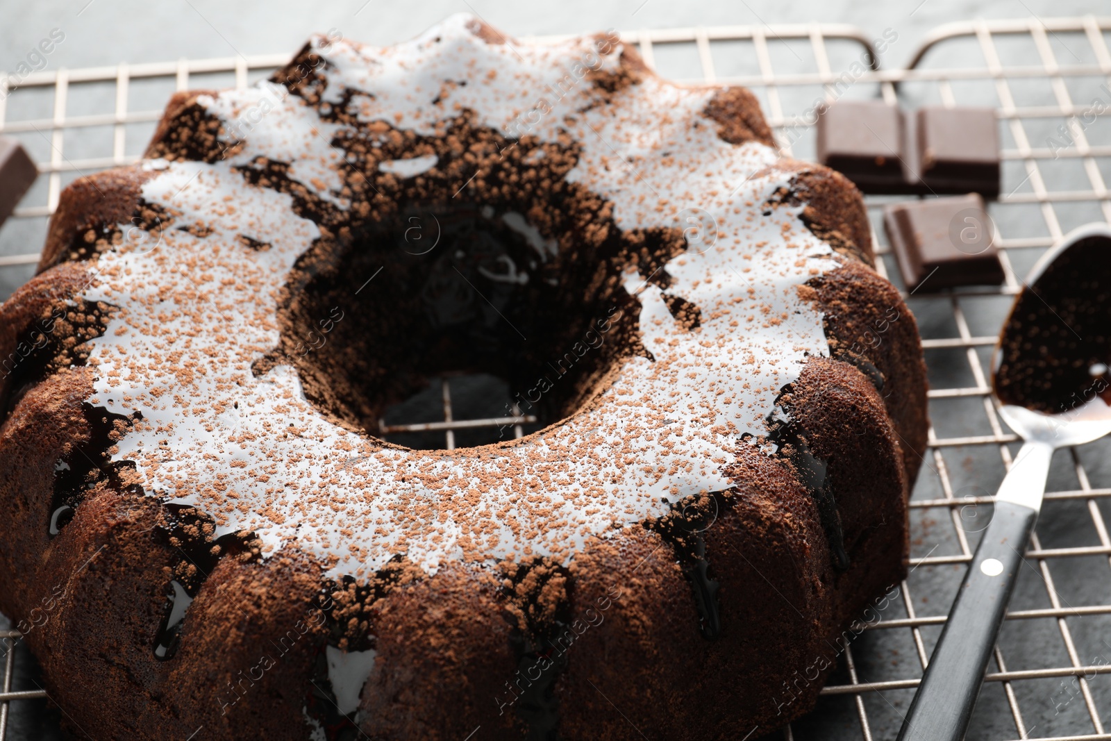 Tasty bundt cake with glaze and chocolate pieces on grey table, closeup Photo of Tasty bundt cake with glaze and chocolate pieces on grey table, closeup
