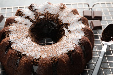 Photo of Tasty bundt cake with glaze and chocolate pieces on grey table, closeup