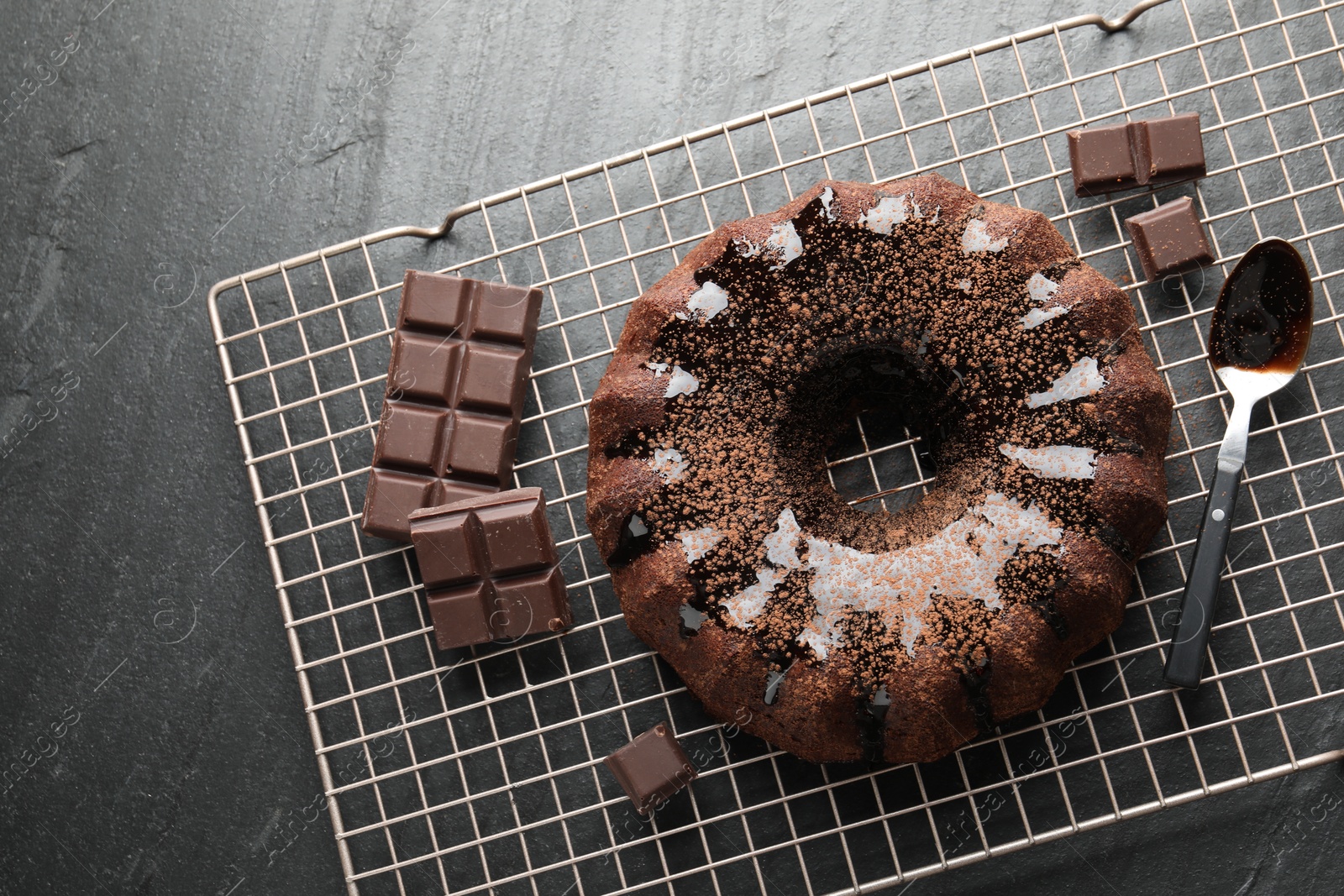 Tasty bundt cake with glaze and chocolate pieces on grey table, top view Photo of Tasty bundt cake with glaze and chocolate pieces on grey table, top view