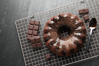 Photo of Tasty bundt cake with glaze and chocolate pieces on grey table, top view