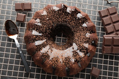 Photo of Tasty bundt cake with glaze and chocolate pieces on grey table, top view