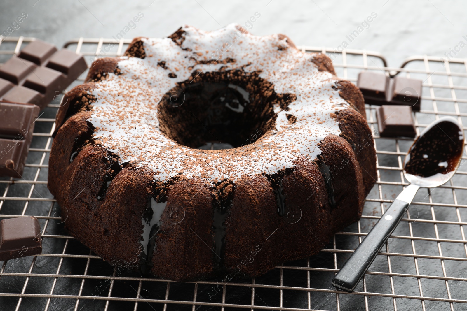 Tasty bundt cake with glaze and chocolate pieces on grey table, closeup Photo of Tasty bundt cake with glaze and chocolate pieces on grey table, closeup