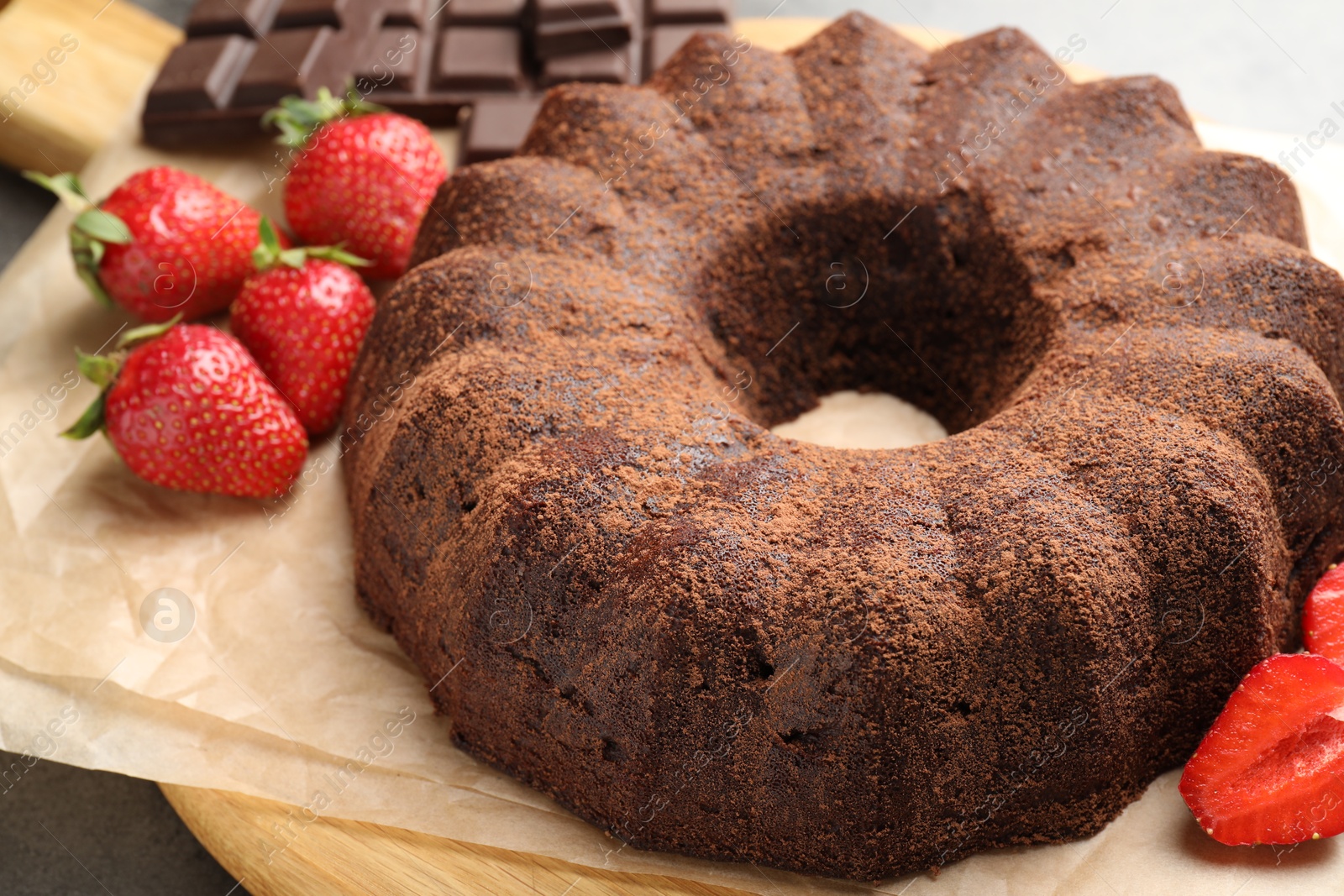 Tasty bundt cake, chocolate pieces and strawberries on grey table, closeup Photo of Tasty bundt cake, chocolate pieces and strawberries on grey table, closeup