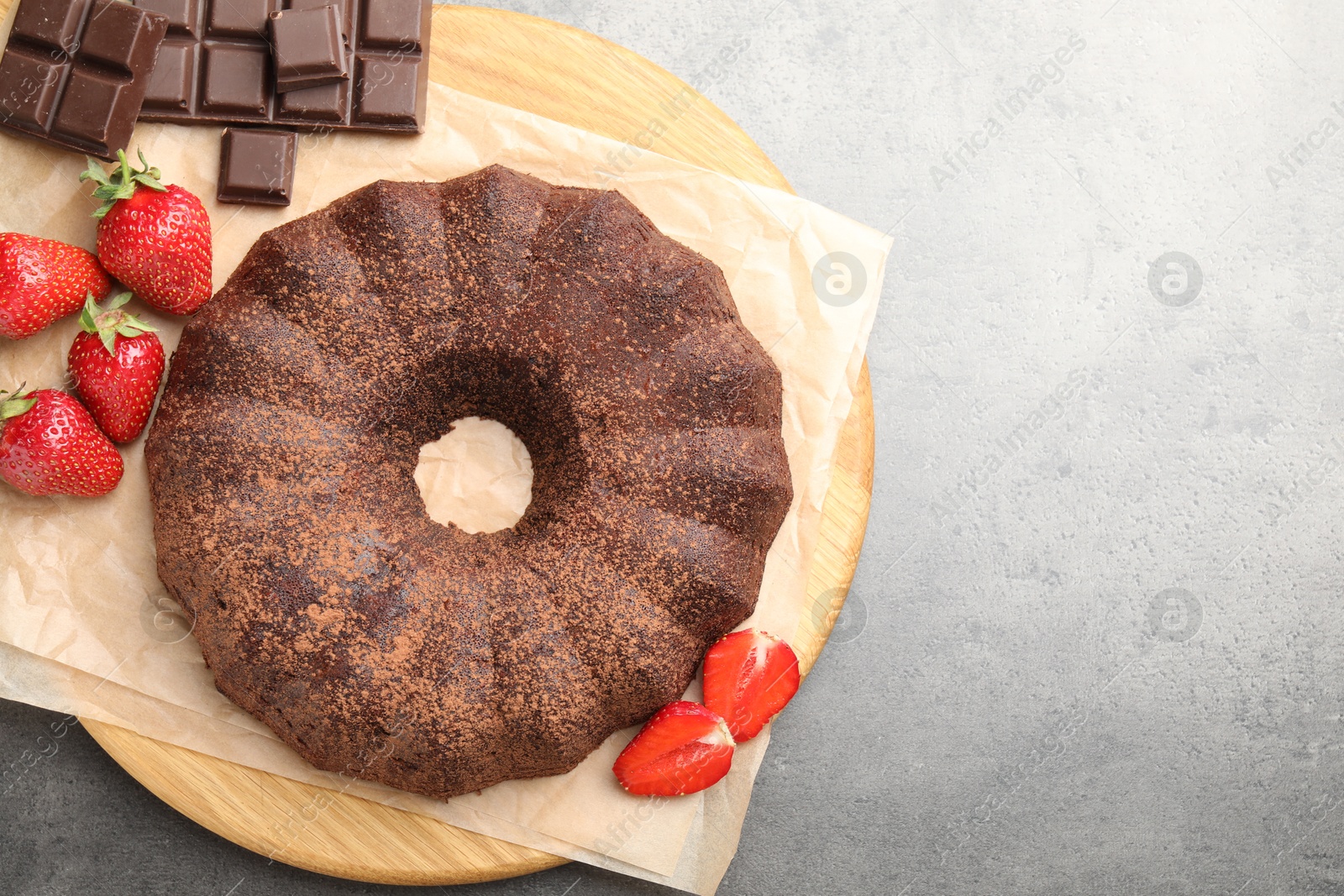 Tasty bundt cake, chocolate pieces and strawberries on grey table, flat lay. Space for text Photo of Tasty bundt cake, chocolate pieces and strawberries on grey table, flat lay. Space for text