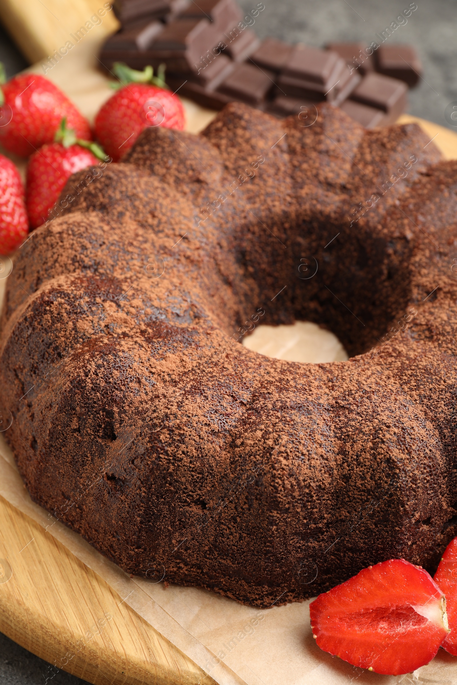 Tasty bundt cake, chocolate pieces and strawberries on grey table, closeup Photo of Tasty bundt cake, chocolate pieces and strawberries on grey table, closeup