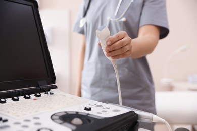 Photo of Sonographer with transducer and ultrasound machine in clinic, closeup