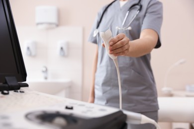 Photo of Sonographer with transducer and ultrasound machine in clinic, closeup